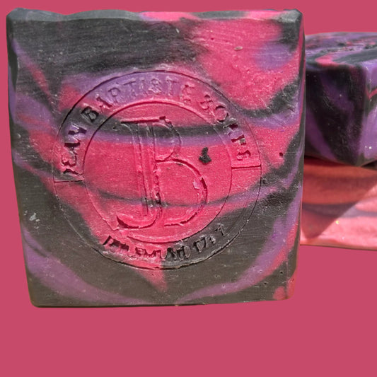 Three bars of soap with a marbled design on a wooden surface, featuring a brand logo.